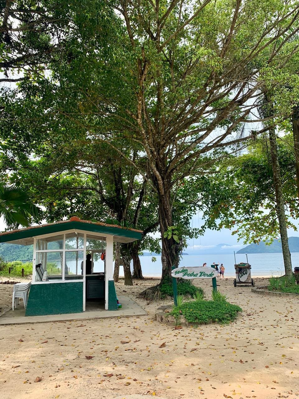 Guarita e placa Pedra Verde na entrada da praia, sob árvores