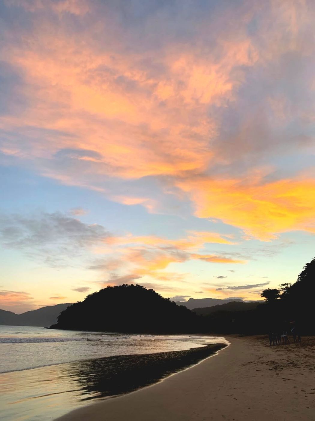 Entardecer na Praia do Lázaro, céu laranja e morro ao fundo