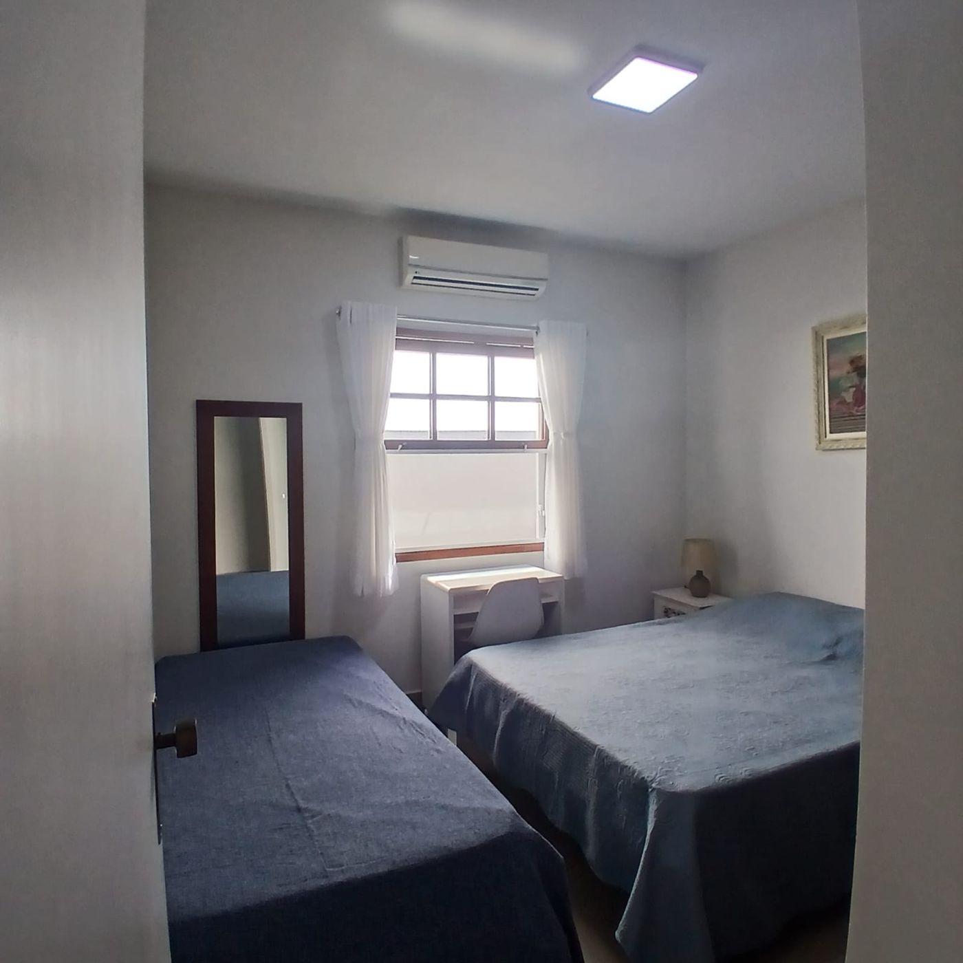 Quarto com cama de casal, cama de solteiro, escrivaninha e janela