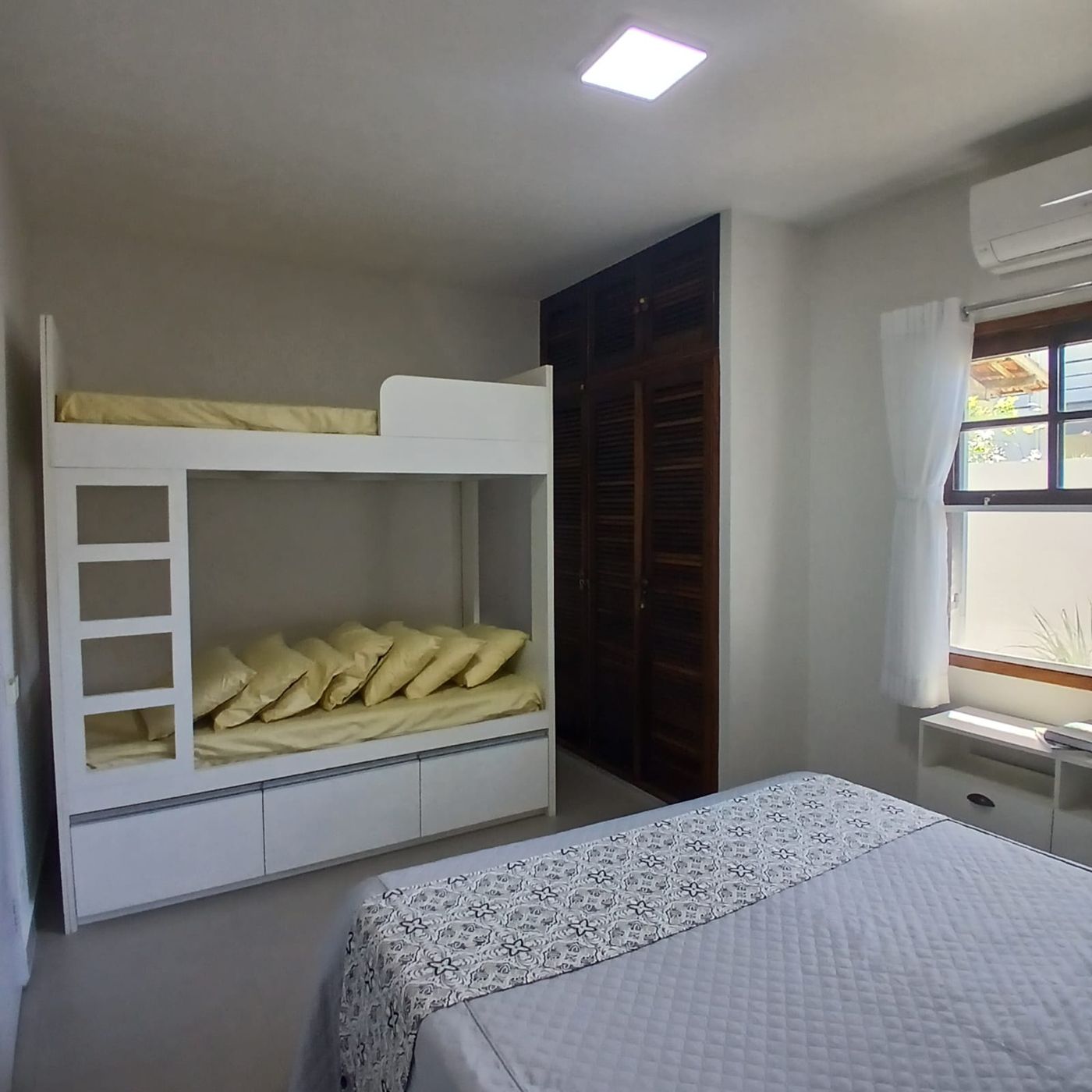 Quarto com beliche branca com gavetas e cama de casal