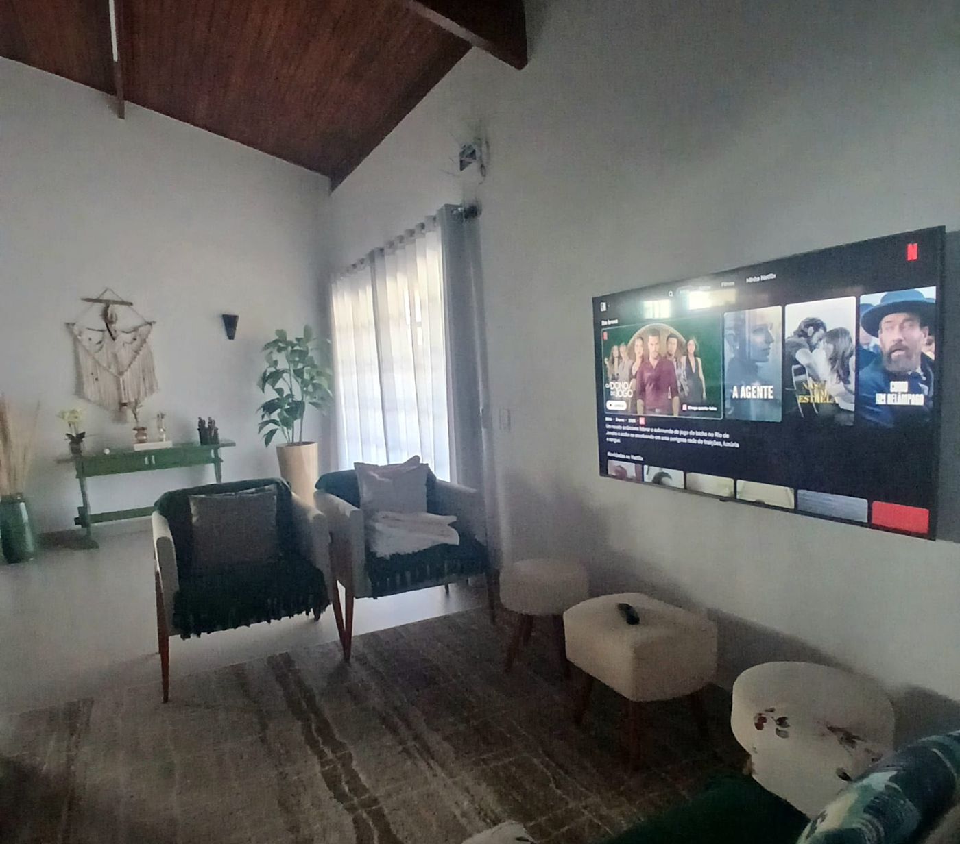 Sala de estar com sofás e TV na parede