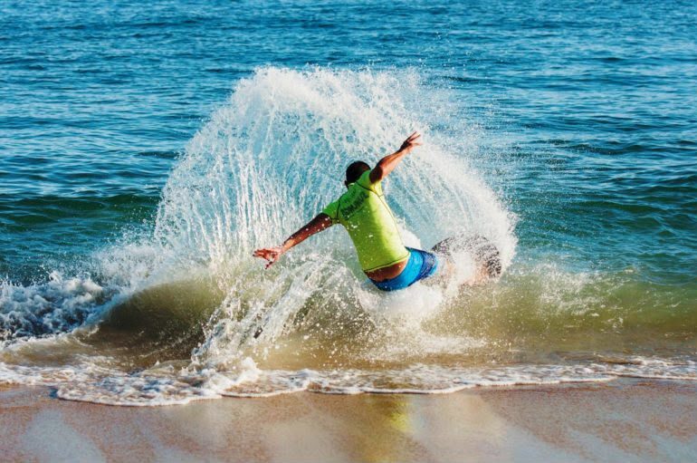 Skimboarder fazendo manobra na beira do mar