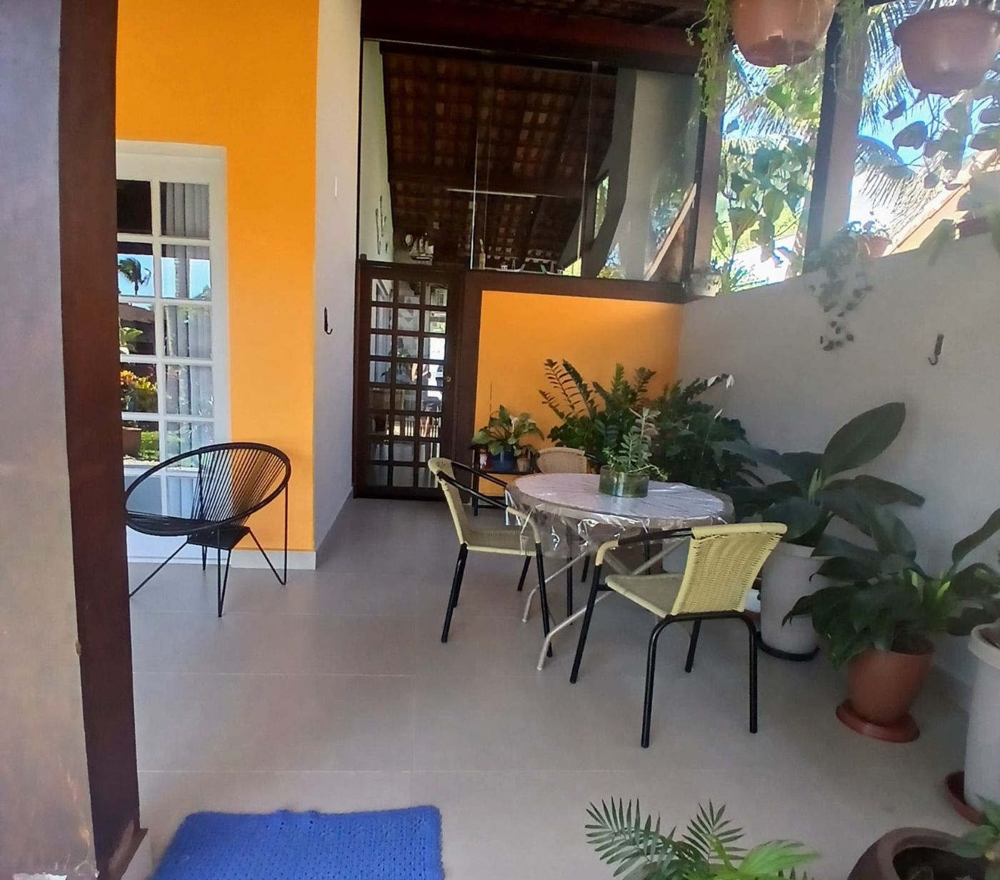 Varanda ampla com rede, mesa e cadeiras, jardim ao fundo